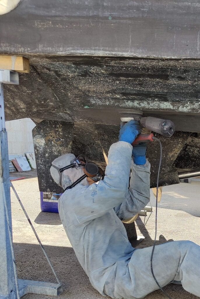 Operatore al lavoro sulla carena di una barca
